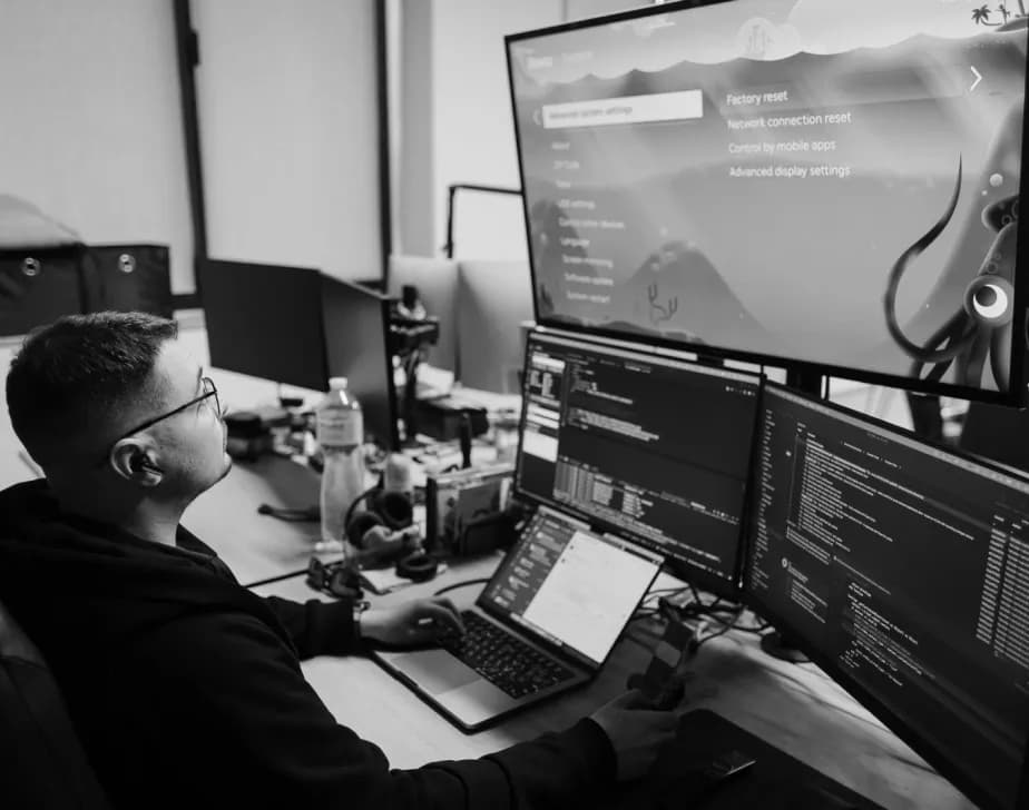 Developer at a desk with several monitors of code and a design